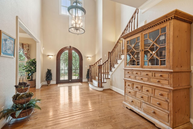 foyer entrance featuring stairs, french doors, light wood finished floors, and a healthy amount of sunlight