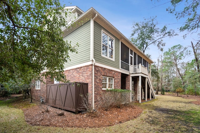 view of side of property with a yard, brick siding, and a sunroom