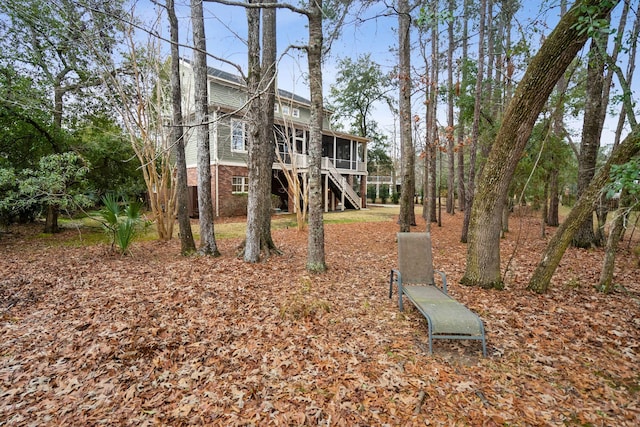 back of house featuring a sunroom, brick siding, and stairway