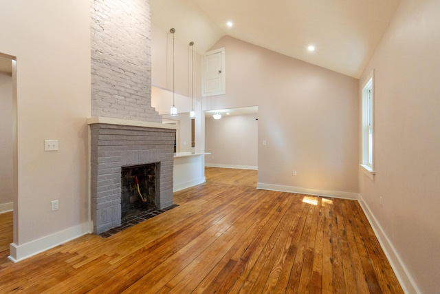708 S Laurel St, Summerville, SC 29483 - unfurnished living room featuring wood-type flooring, baseboards, high vaulted ceiling, and a brick fireplace