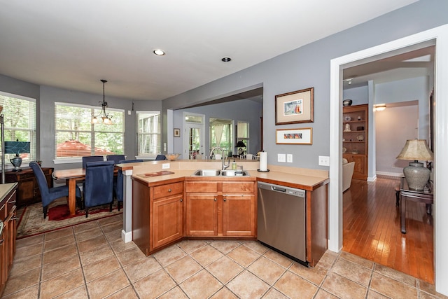 477 Commonwealth Rd, Mount Pleasant, SC 29466 - kitchen with stainless steel dishwasher, light countertops, brown cabinetry, hanging light fixtures, and a peninsula