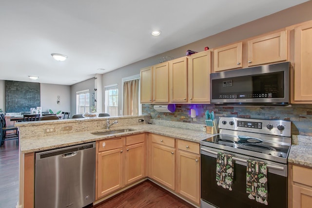 kitchen featuring dark wood-style flooring, a peninsula, appliances with stainless steel finishes, a sink, and light brown cabinetry