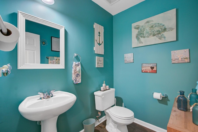 bathroom with visible vents, toilet, wood finished floors, a sink, and baseboards