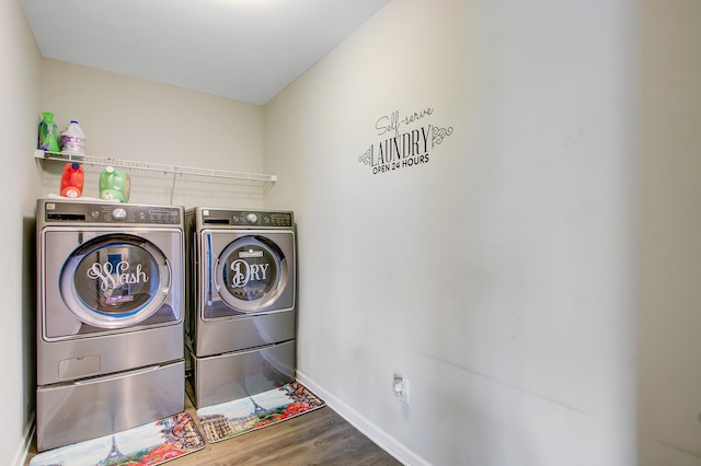 clothes washing area featuring laundry area, wood finished floors, baseboards, and washer and clothes dryer