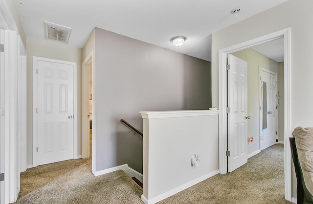 hallway featuring an upstairs landing, visible vents, baseboards, and carpet