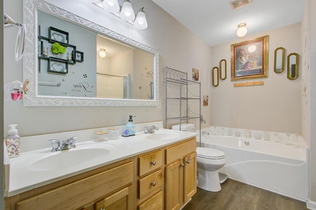full bath featuring toilet, wood finished floors, a sink, and a garden tub