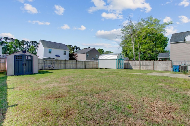view of yard with an outbuilding, a fenced backyard, central air condition unit, and a storage unit