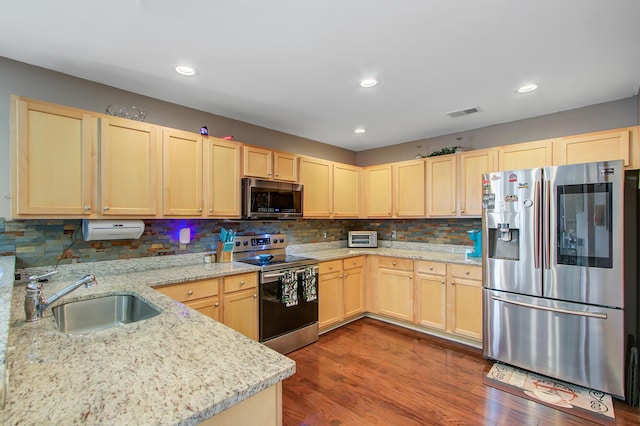kitchen featuring tasteful backsplash, dark wood finished floors, stainless steel appliances, a sink, and light brown cabinetry