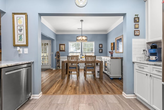 dining area with an inviting chandelier, ornamental molding, and light hardwood / wood-style floors