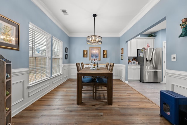 dining space featuring a notable chandelier, ornamental molding, and light hardwood / wood-style floors