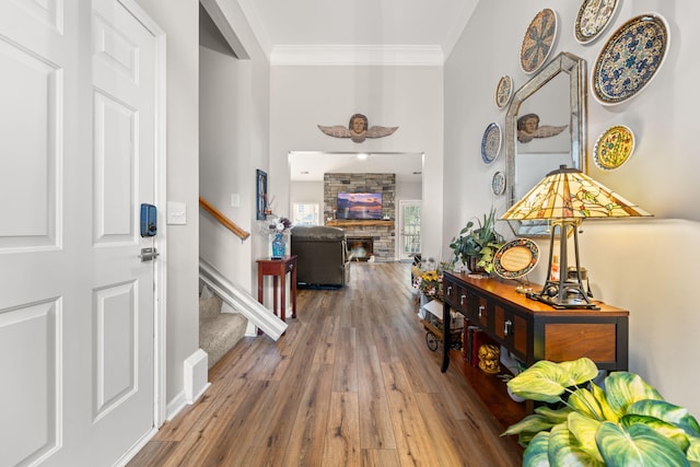 entryway featuring crown molding, a stone fireplace, and hardwood / wood-style flooring