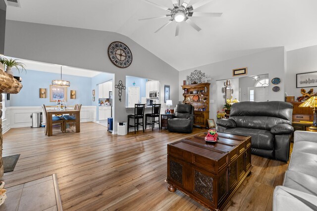 living room featuring high vaulted ceiling, light hardwood / wood-style floors, and ceiling fan