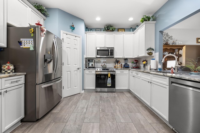 kitchen featuring light stone counters, tasteful backsplash, stainless steel appliances, and white cabinets