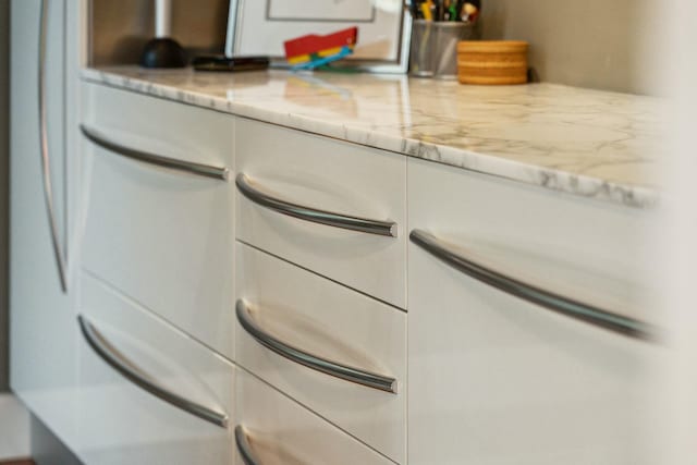 interior details featuring light stone countertops and white cabinets