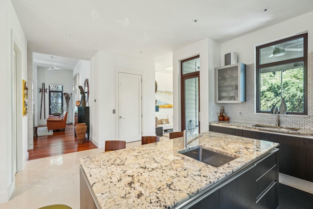 kitchen featuring light stone countertops, light tile patterned floors, a kitchen island with sink, and sink