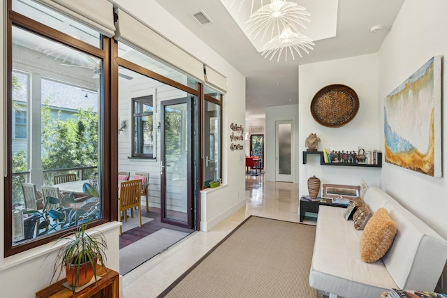 doorway to outside featuring a wealth of natural light, light tile patterned floors, and a chandelier