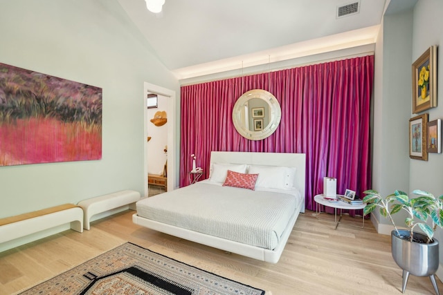 bedroom featuring lofted ceiling, wood-type flooring, and ensuite bath