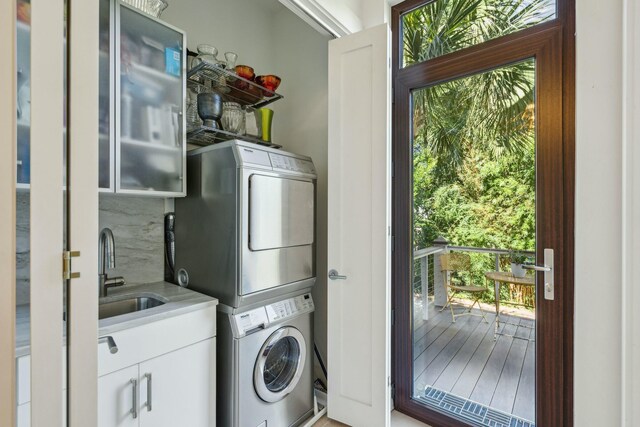 laundry room featuring cabinets, stacked washer and dryer, and sink