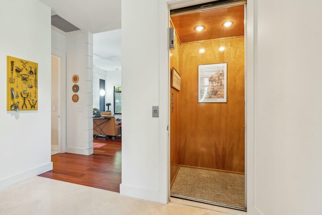 hall with tile patterned flooring and elevator