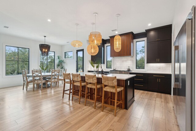 231 Bayview Dr, Mount Pleasant, SC 29464 - kitchen with appliances with stainless steel finishes, decorative backsplash, light countertops, a center island with sink, and a breakfast bar area