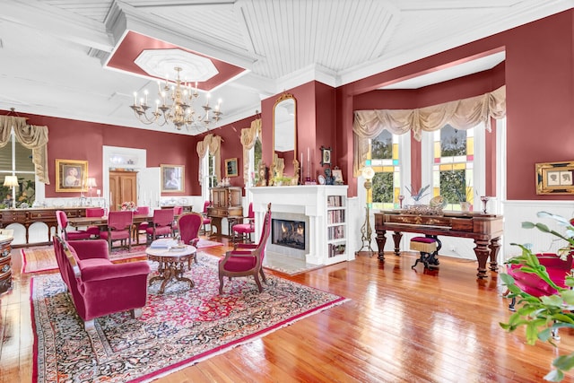 living area with an inviting chandelier, a fireplace with flush hearth, and hardwood / wood-style floors