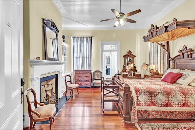 bedroom featuring hardwood / wood-style floors, a fireplace, and crown molding