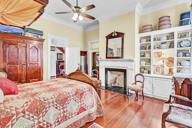 bedroom with light wood-style floors, a fireplace, ornamental molding, and a ceiling fan