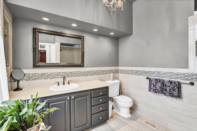 bathroom featuring toilet, tile walls, and vanity