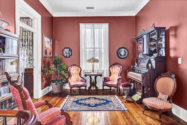 living area featuring wood-type flooring, visible vents, crown molding, and baseboards