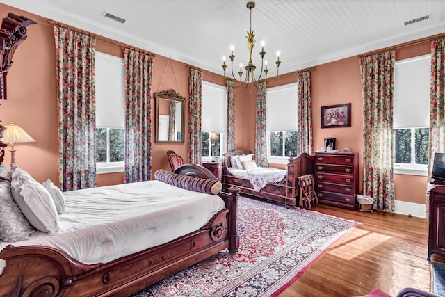 bedroom featuring a chandelier, wood finished floors, visible vents, and baseboards