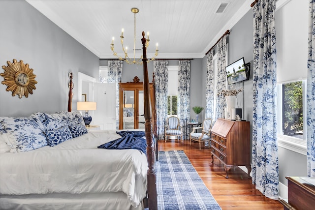 bedroom with ornamental molding, a chandelier, visible vents, and wood finished floors