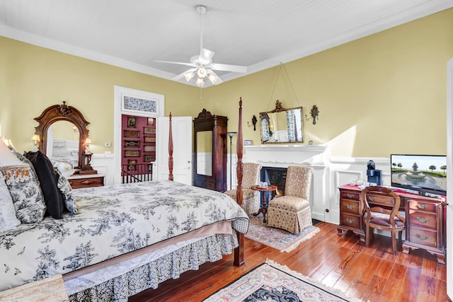 bedroom featuring wood-type flooring, a fireplace, a decorative wall, and wainscoting