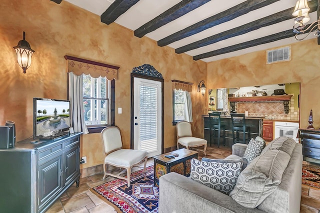 living room with beam ceiling, visible vents, and stone tile floors