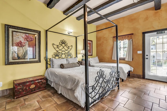 bedroom with stone finish flooring, baseboards, and beam ceiling