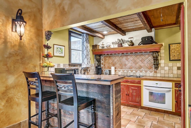 bar featuring white oven, beamed ceiling, wood ceiling, and tasteful backsplash