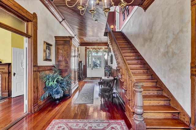 entryway with a chandelier, wooden ceiling, stairs, ornamental molding, and wood-type flooring