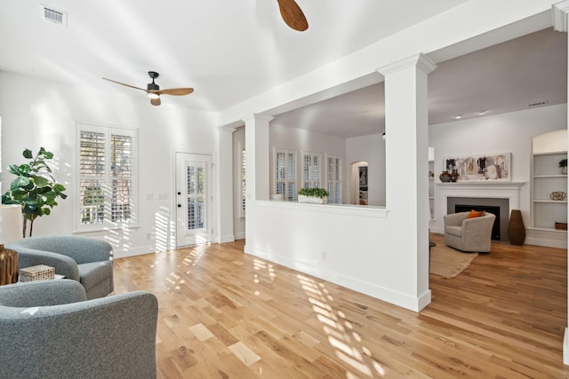 living room featuring wood-type flooring, decorative columns, and ceiling fan