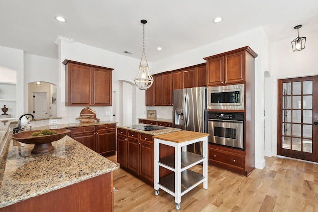 kitchen featuring sink, stainless steel appliances, light stone counters, decorative backsplash, and decorative light fixtures