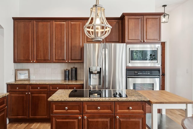 kitchen featuring pendant lighting, tasteful backsplash, light stone counters, stainless steel appliances, and light wood-type flooring