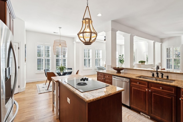 kitchen featuring ornate columns, appliances with stainless steel finishes, decorative light fixtures, sink, and a center island