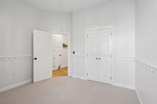 unfurnished bedroom with light carpet and a closet