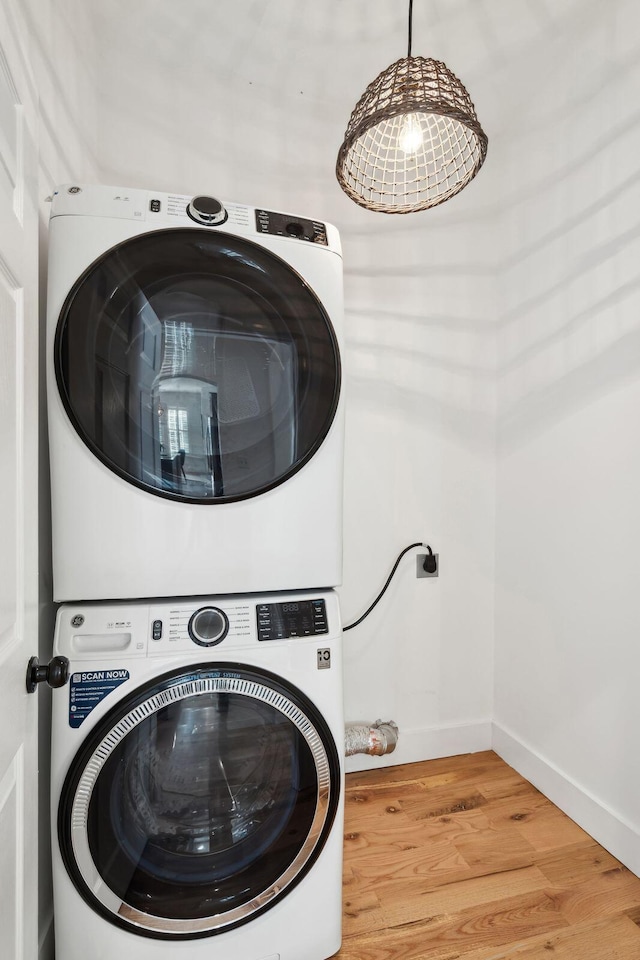 washroom featuring hardwood / wood-style flooring and stacked washer / drying machine