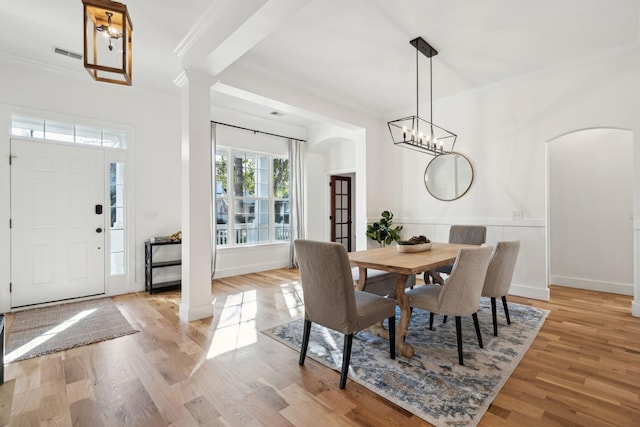 dining space featuring ornate columns, crown molding, and light hardwood / wood-style floors