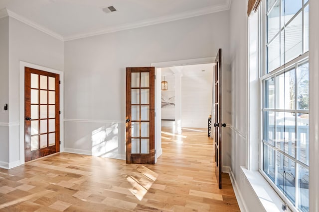 doorway with french doors, ornamental molding, and light hardwood / wood-style flooring