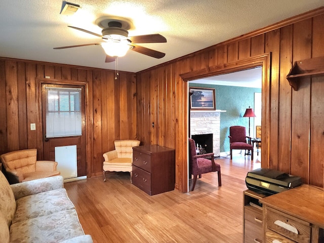 1216 Eastwood Ave, Hanahan, SC 29410 - living area featuring light wood-style floors, wood walls, ceiling fan, and a fireplace