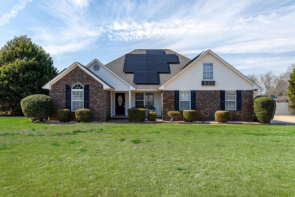 3155 Caitlynn Dr, Sumter, SC 29154 - view of front of property featuring a shingled roof, a front yard, solar panels, and brick siding