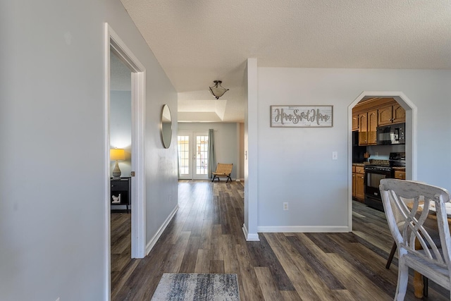 corridor featuring french doors, dark wood finished floors, a textured ceiling, and baseboards