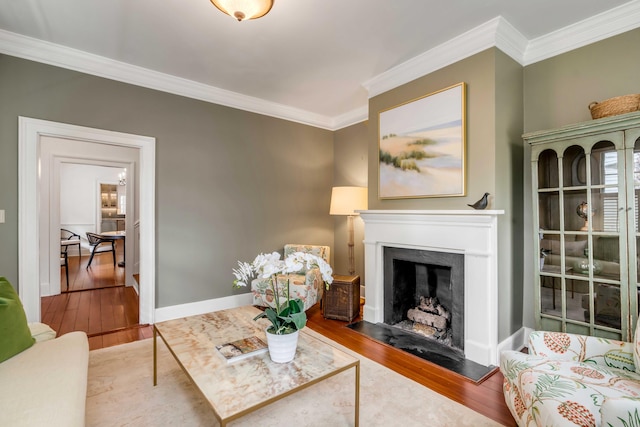 living area featuring ornamental molding, a fireplace, wood finished floors, and baseboards