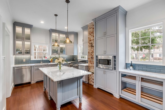 kitchen with appliances with stainless steel finishes, gray cabinets, a sink, and dark wood-style flooring