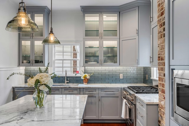 kitchen with light stone countertops, gray cabinets, stainless steel appliances, and a sink